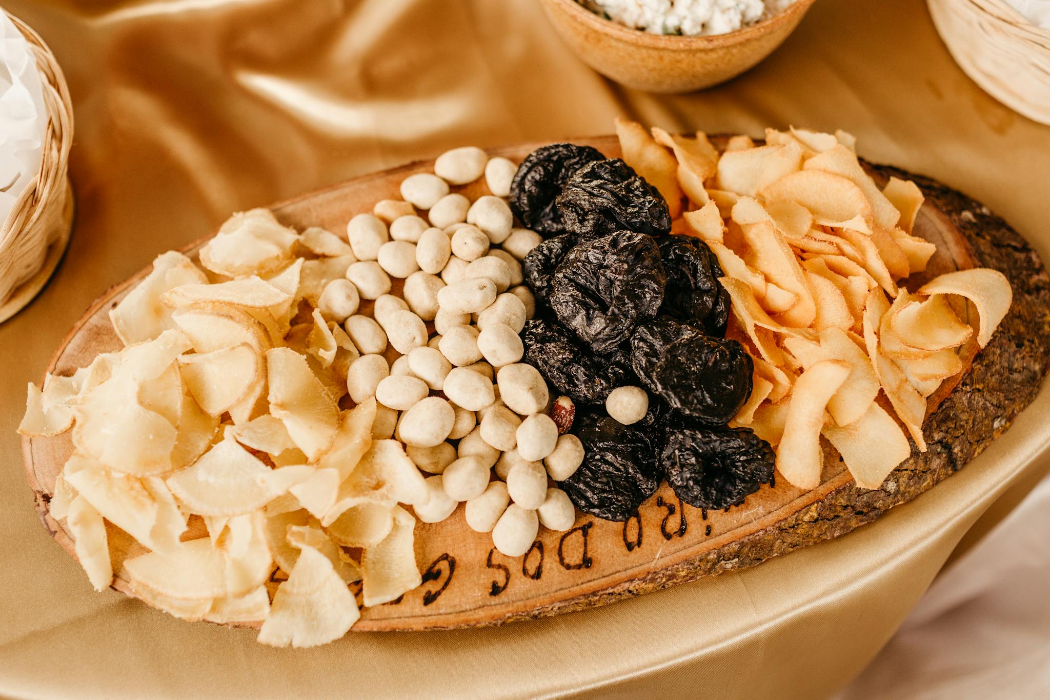 A close-up of assorted dried fruits and nuts arranged on a rustic wooden tray.