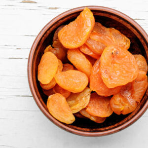 Delicious dried apricots in a bowl on white background