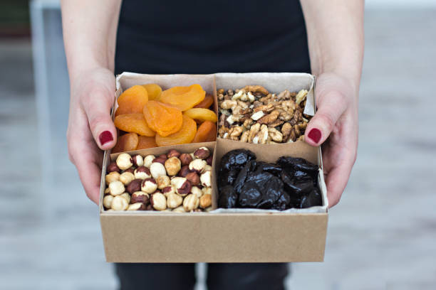 Female hands hold a box of nuts and dried fruits.