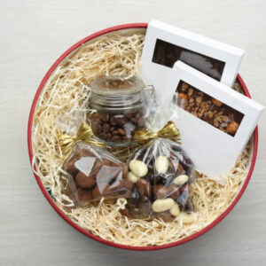 Gift box with chocolate and sweets on white wooden table, top view