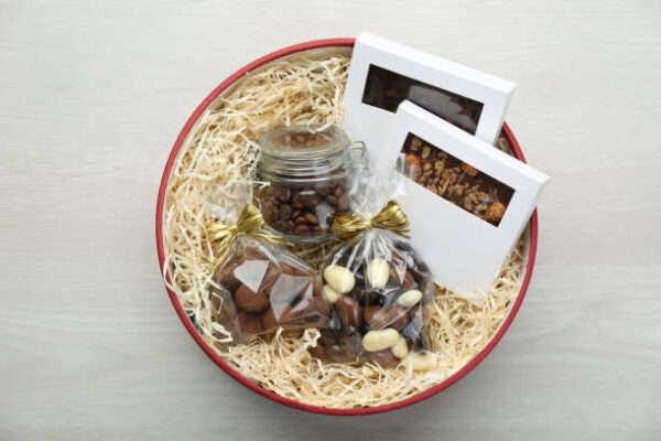 Gift box with chocolate and sweets on white wooden table, top view
